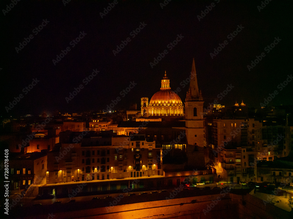 St. Paul's Cathedral and illuminated Basilica dome at dark night. Aerial view from the sea in Valletta.