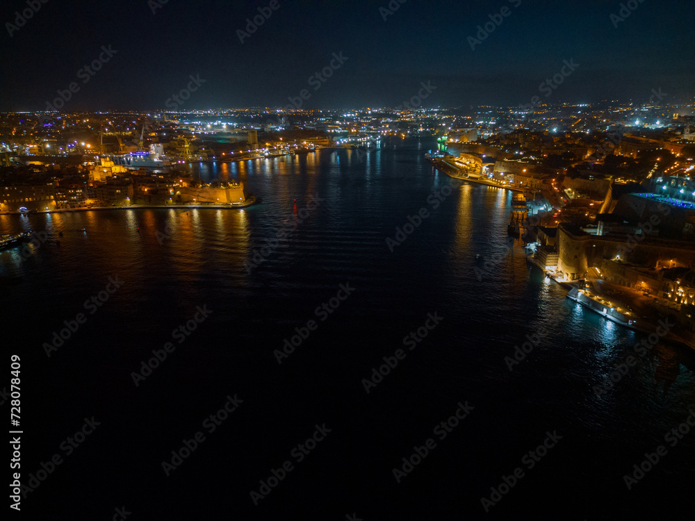 Night panoramic view of Valletta coastline waterfront lights with reflection on the sea.  Aerial view towards Gardjola Gardens and the docks.