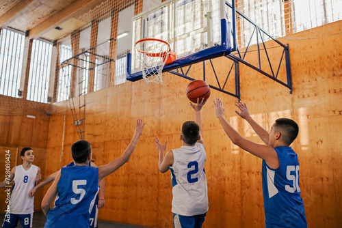 Junior basketball players shooting a ball at the hoop during their training. © Zamrznuti tonovi