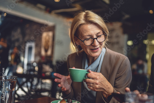 one mature caucasian blonde woman have a cup of coffee sit at cafe