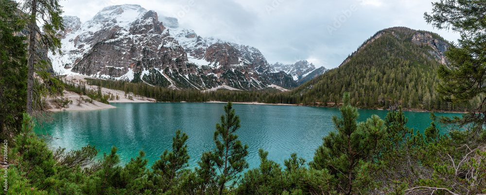 Panoramic view of turquoise water alpine lake Lago di Braies in Dolomities mountains, Belluno, Veneto, Italy on moody spring day. Lake in the forest in Dolomiti in Italian Alps
