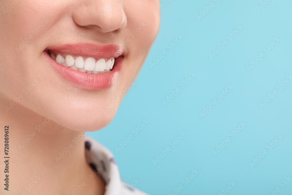 Woman with clean teeth smiling on light blue background, closeup. Space for text Woman with clean teeth smiling on light blue background, closeup. Space for text