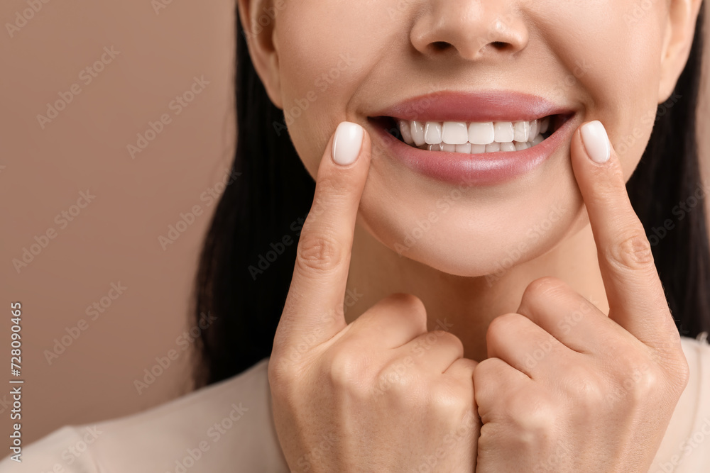 Woman showing her clean teeth and smiling on beige background, closeup Woman showing her clean teeth and smiling on beige background, closeup