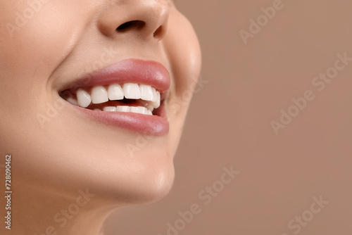Woman with clean teeth smiling on beige background  closeup. Space for text