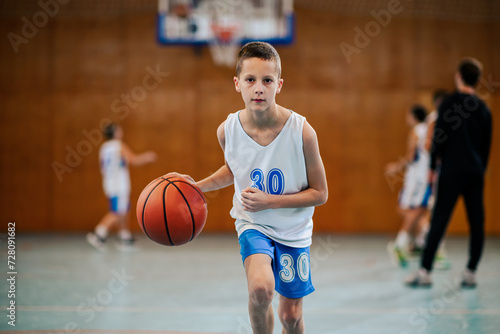 A junior basketball player in action dribbling a ball towards camera.