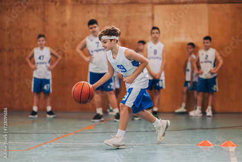 A junior basketball player dribbling a ball and practicing on court.