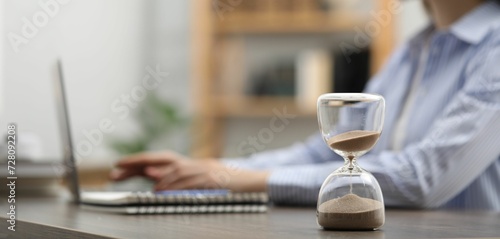 Tableau sur toile Hourglass with flowing sand on desk