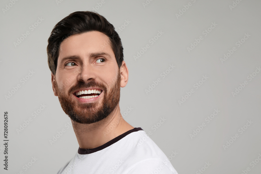 Obraz premium Portrait of smiling man with healthy clean teeth on light grey background. Space for text