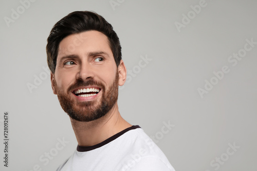 Portrait of smiling man with healthy clean teeth on light grey background. Space for text