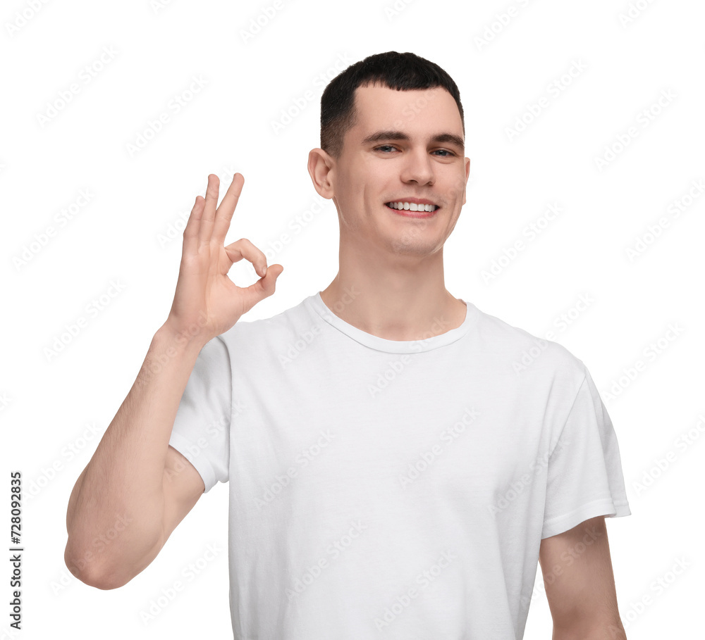 Handsome young man with clean teeth smiling and showing OK gesture on white background Handsome young man with clean teeth smiling and showing OK gesture on white background