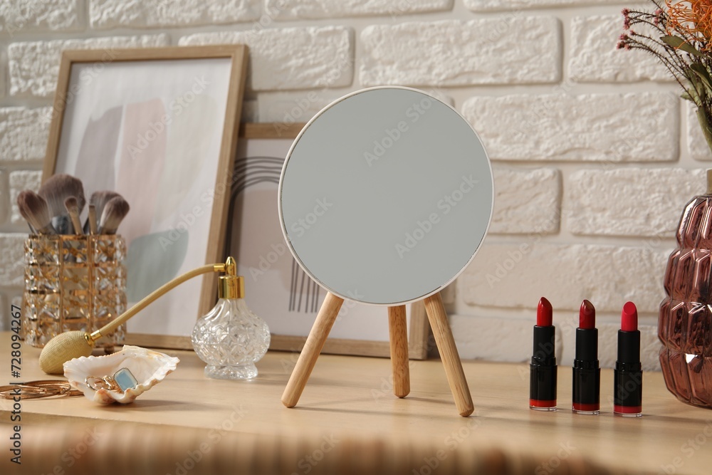 Mirror, makeup products, perfume and jewelry on wooden dressing table