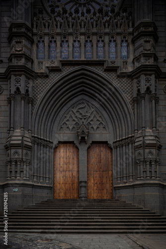 SPAIN, Gran Canaria, Arucas: Neo-Gothic religious architecture charm in the stone facade of San Juan Bautista Church, entrance doors to a timeless historic architectural gem in the heart of the town.