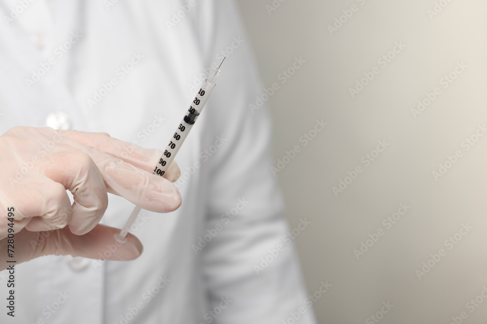 Doctor holding syringe on grey background, closeup. Space for text Doctor holding syringe on grey background, closeup. Space for text