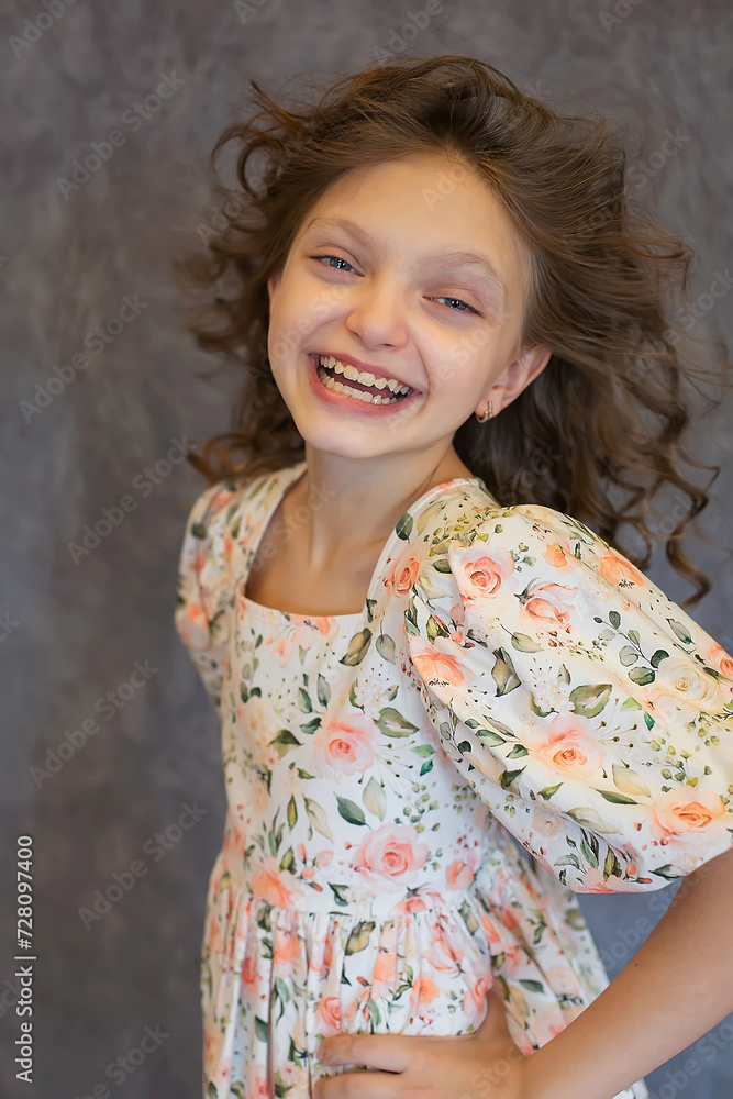A happy teenage girl with curly hair and big blue eyes in a floral print dress A happy teenage girl with curly hair and big blue eyes in a floral print dress