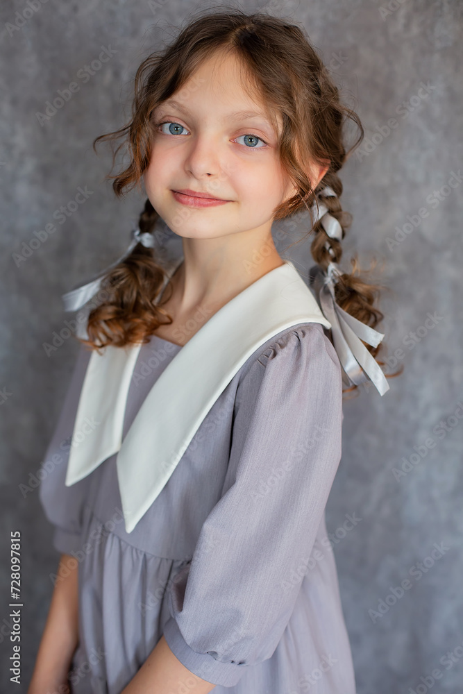Beautiful teenage girl with big blue eyes pigtails and a gray school dress with a white collar