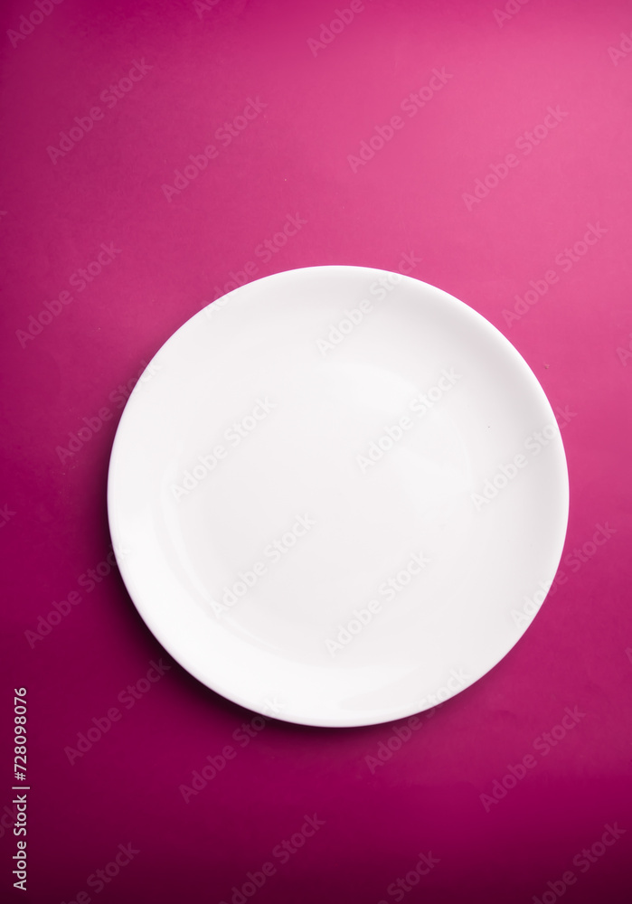 White flat plate on a purple background. View from above White flat plate on a purple background. View from above