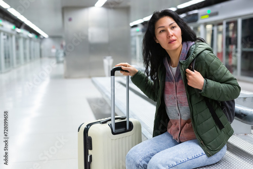 Fotografie Asian woman sitting in subway station and waiting for train arrival