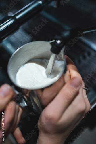 barista heating fresh milk for making cappuccino or latte coffee hot drink