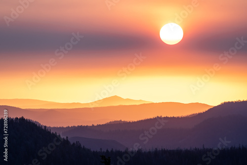 Clouds Dim Sunrise Over Layers of Mountains and Forest In Lassen