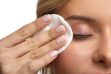 Woman removing makeup with cotton pad on white background, closeup