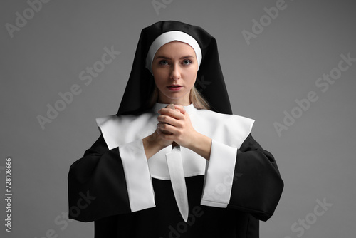 Woman in nun habit holding knife on grey background photo