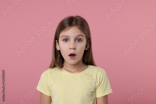Portrait of surprised girl on pink background photo