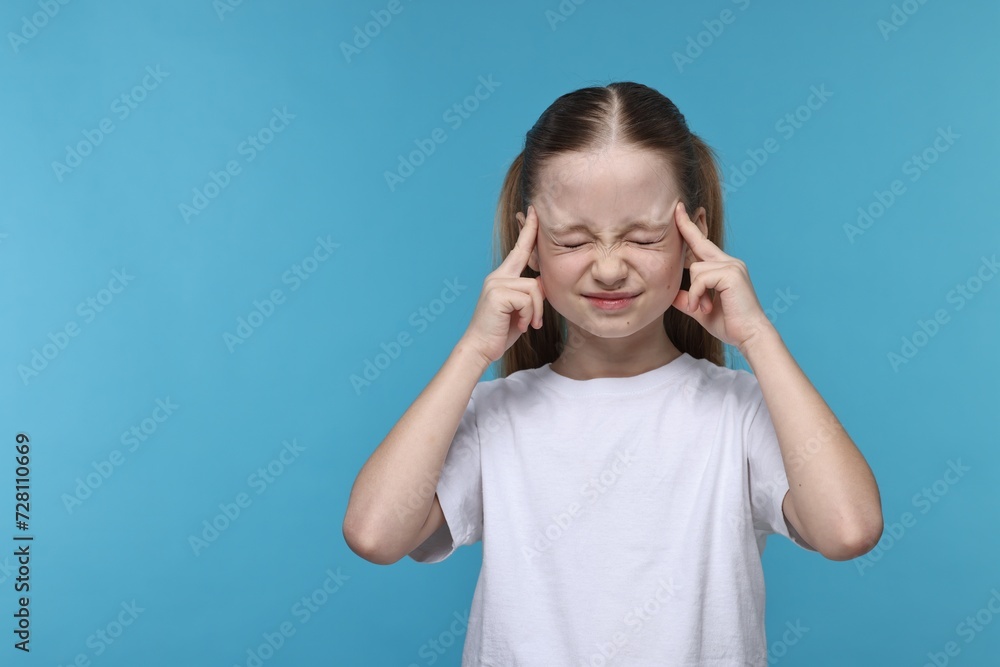 Little girl suffering from headache on light blue background. Space for text Little girl suffering from headache on light blue background. Space for text