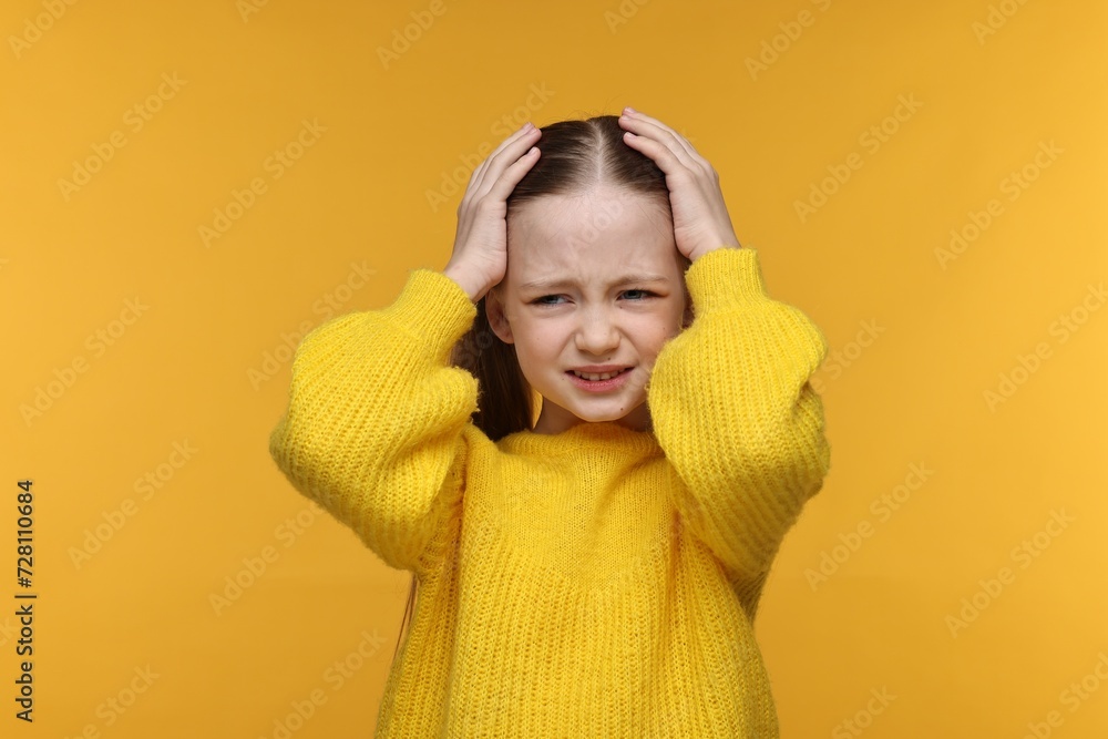 Little girl suffering from headache on yellow background Little girl suffering from headache on yellow background