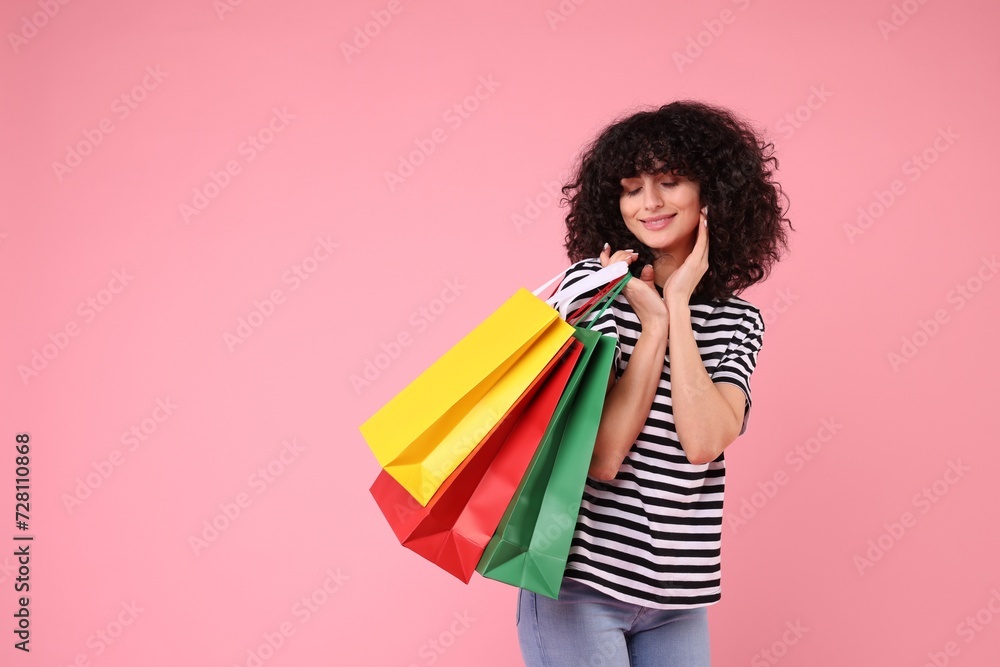Happy young woman with shopping bags on pink background. Space for text Happy young woman with shopping bags on pink background. Space for text