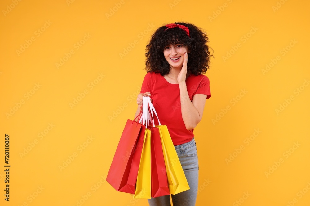 Happy young woman with shopping bags on yellow background Happy young woman with shopping bags on yellow background