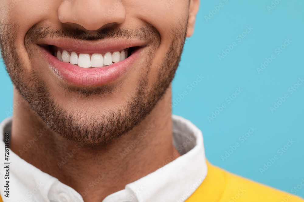 Fototapeta premium Smiling man with healthy clean teeth on light blue background, closeup