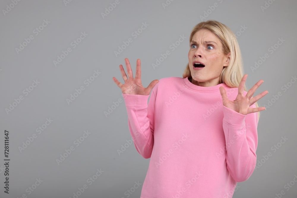 Portrait of surprised woman on grey background, space for text Portrait of surprised woman on grey background, space for text