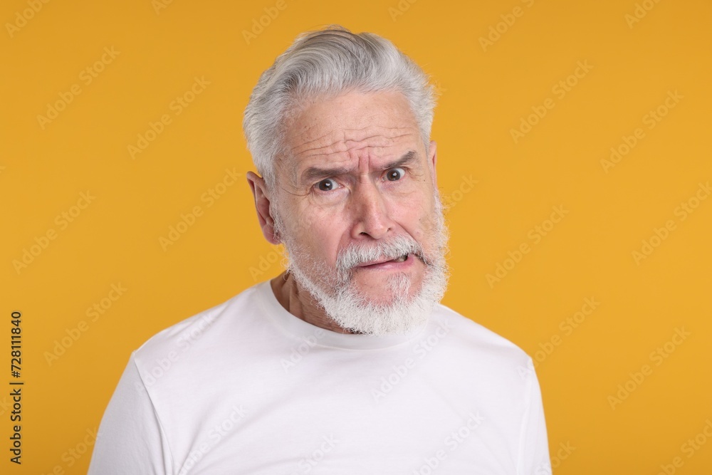 Portrait of surprised senior man on yellow background Portrait of surprised senior man on yellow background