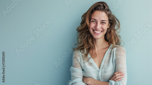 A happy, successful woman in a casual outfit, smiling confidently at the camera against a pale blue background. She exudes a sense of contentment and accomplishment.