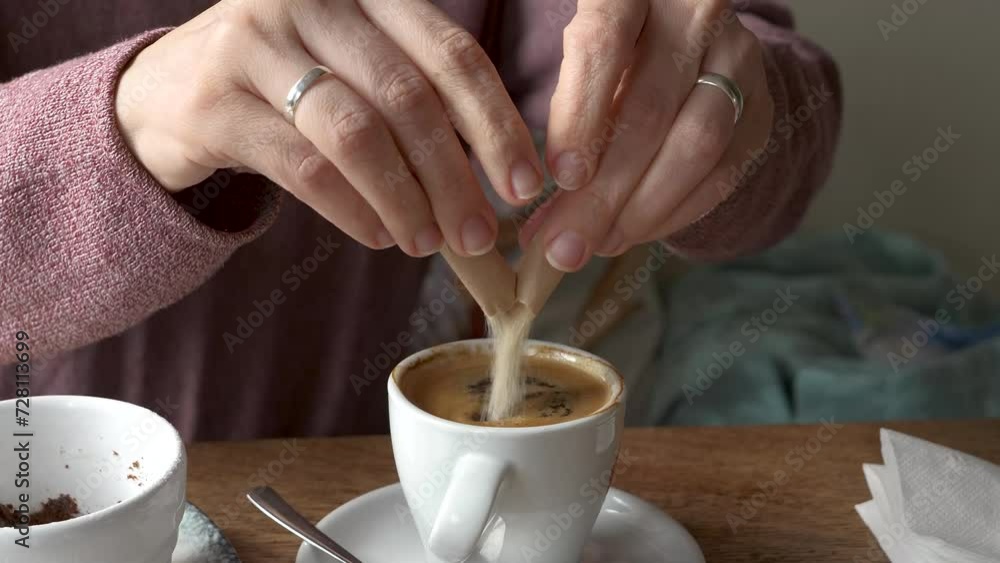 A close-up video showing a woman tearing open a brown sugar paper stick and sweetening her coffee in a white espresso cup, capturing a cozy, homemade beverage moment. A close-up video showing a woman tearing open a brown sugar paper stick and sweetening her coffee in a white espresso cup, capturing a cozy, homemade beverage moment.