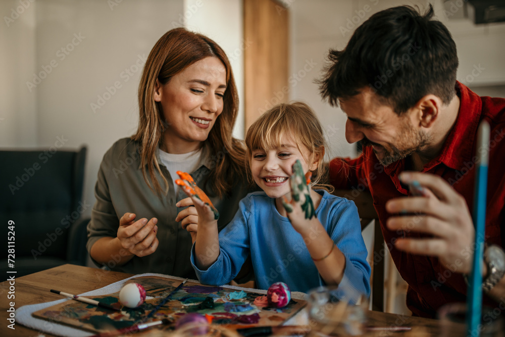 Fototapeta premium Three-person family enjoying a delightful Easter egg painting session in their dining room
