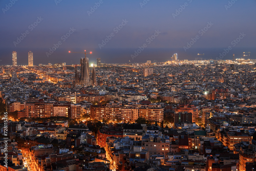 As twilight falls over Barcelona, the Sagrada Familia's spires tower above lit streets and modern towers like Torre Glories. The city's grid and coastal glow enhance the urban scene.
