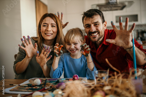 Three-person family enjoying a delightful Easter egg painting session in their dining room