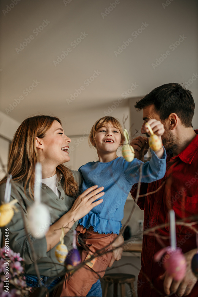 Parents and their child decorating eggs with bright hues, surrounded by the festive atmosphere of their dining room