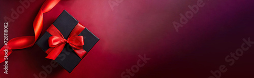 Black gift box decorated with red ribbon, view from above, isolated on red background, ideal for advertising products on Black Friday or Cyber Monday. Panorama with large copy space.