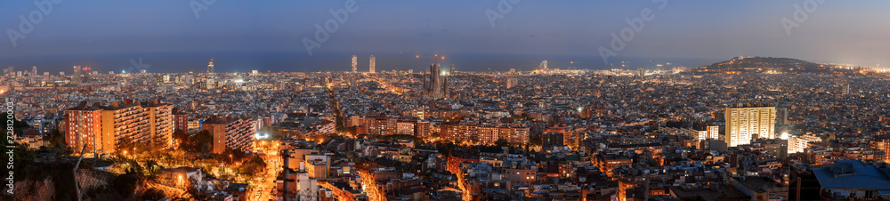 Panoramic evening view of Barcelona, Spain, showcasing its urban glow with lit streets and buildings against a dusk sky, hinting at its coastal setting and vibrant nightlife.