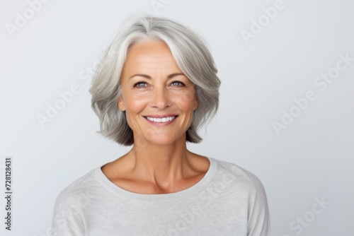 Portrait of a happy senior woman looking at the camera over grey background