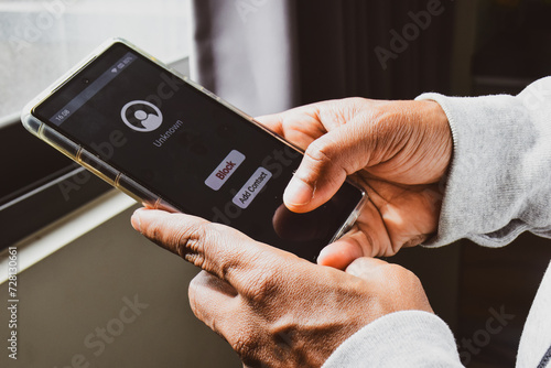 Man deciding to block unknown caller phone number to prevent voice phishing scam. Selective focus.	 photo