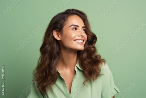 Portrait of happy smiling beautiful young brunette woman in green shirt, over green background