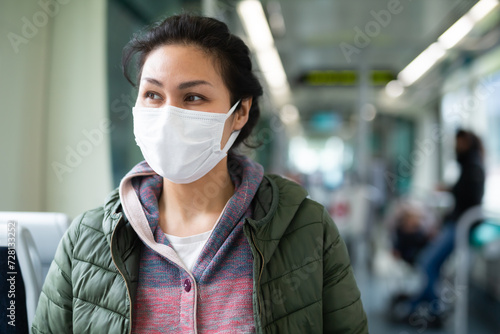 Portrait of young adult woman wearing face mask for prevent illness inside modern city tram