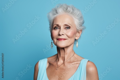 Portrait of beautiful senior woman on blue background. Beauty, fashion.