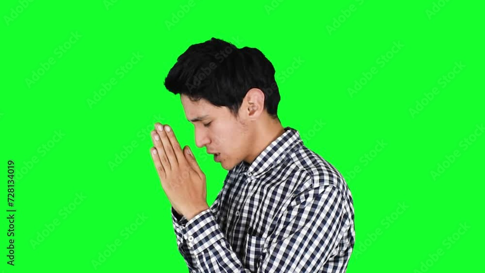 Joven hombre delgado caucasico orando sobre un fondo verde aislado Joven hombre delgado caucasico orando sobre un fondo verde aislado