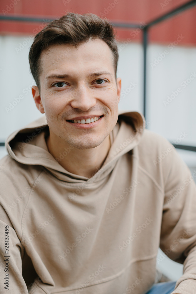 Cheerful young man sitting on the stairs on the street, looking at the camera. Cheerful young man sitting on the stairs on the street, looking at the camera.