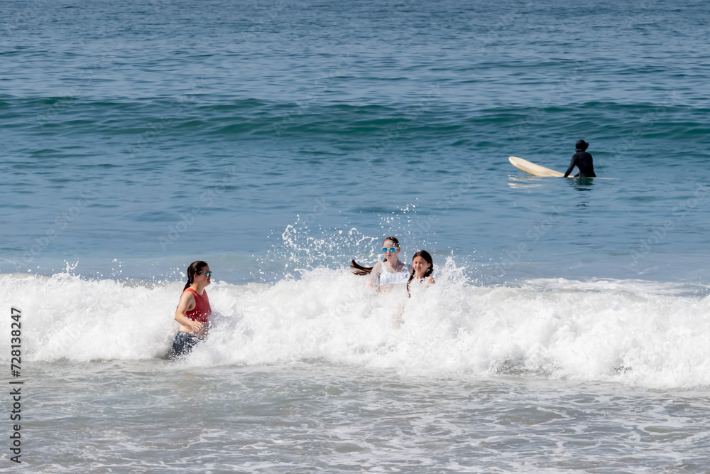 Four People Playing in Beach Waves at Sunset Beach, California, USA, horizontal Four People Playing in Beach Waves at Sunset Beach, California, USA, horizontal