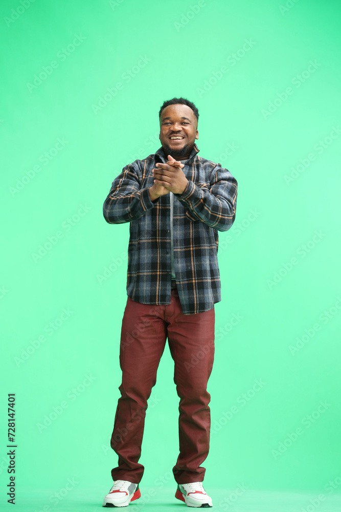 Fototapeta premium A man, full-length, on a green background, claps